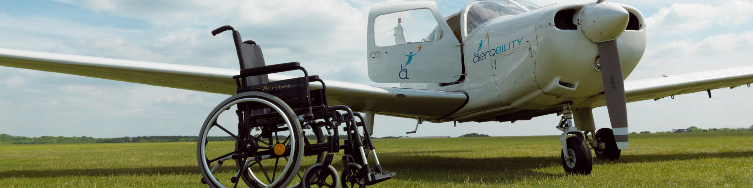 Aerobility, empty wheelchair next to an aeroplane, banner